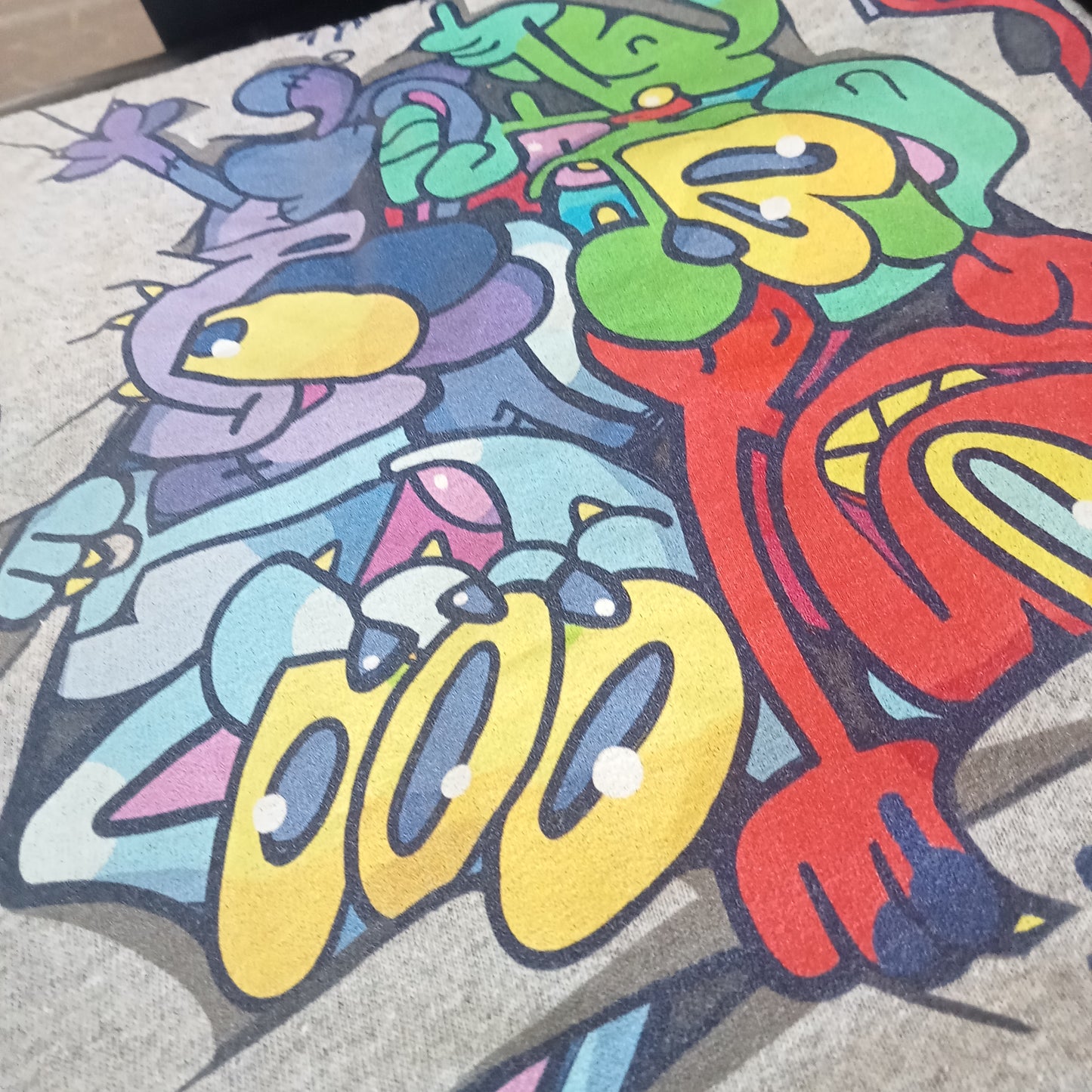 Grey streetwear shirt by indie Brighton-based brand CORKiE, featuring graffiti style characters ripping and tagging on the shirt.