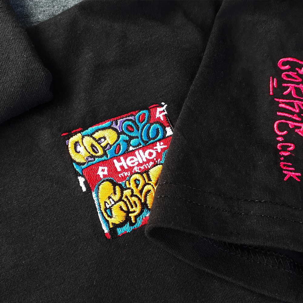'Hello my name is' graffiti sticker embroidery pattern, on a shirt by indie streetwear brand CORKiE, based in Brighton. Also showing a hand style tag of the brand name.