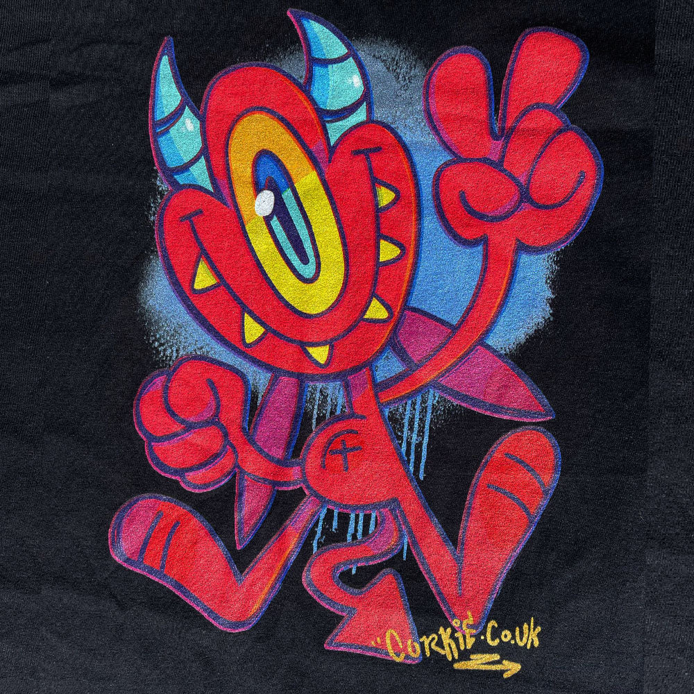 Devil graffiti character by streetwear brand CORKiE, printed onto a black shirt with a spray paint effect in the background.