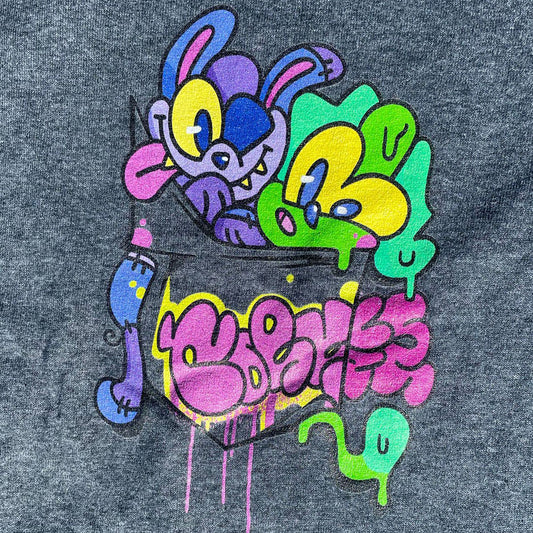 Close up of Indie streetwear brand CORKiE grey t-shirt. Featuring a graphic design with two retro graffiti style characters in the shirts pocket. With a throwie bubble text logo on the sleeve.